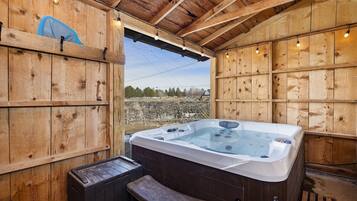 A wooden cabin with a hot tub, wooden benches, and a view of the outdoors.