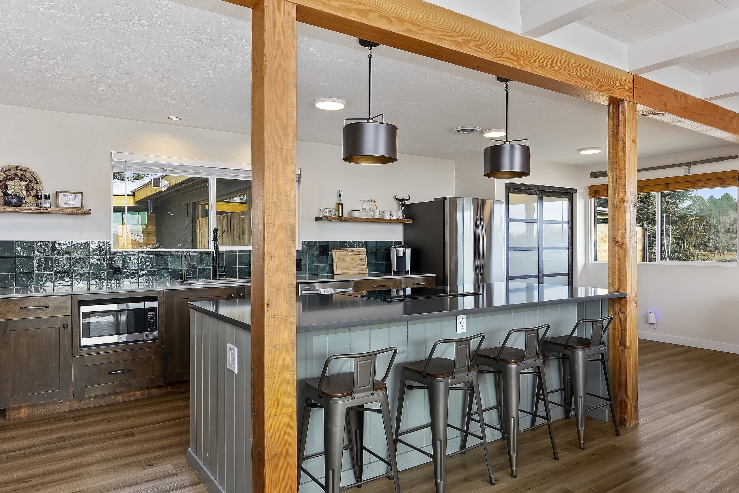 Une cuisine moderne avec un coin bar, des poutres en bois et une grande fenêtre.