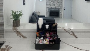 En moderne stue med pejs, en sort sofa, et sofabord og en kurv med snacks.
