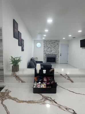 A modern living room with a fireplace, a black sofa, a coffee table, and a snack basket. - Luxury Stay in the Heart of Tampa Bay (Tampa)