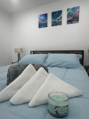 A bed with pillows, a blanket, and a candle. There are three framed pictures on the wall. - Luxury Stay in the Heart of Tampa Bay (Tampa)