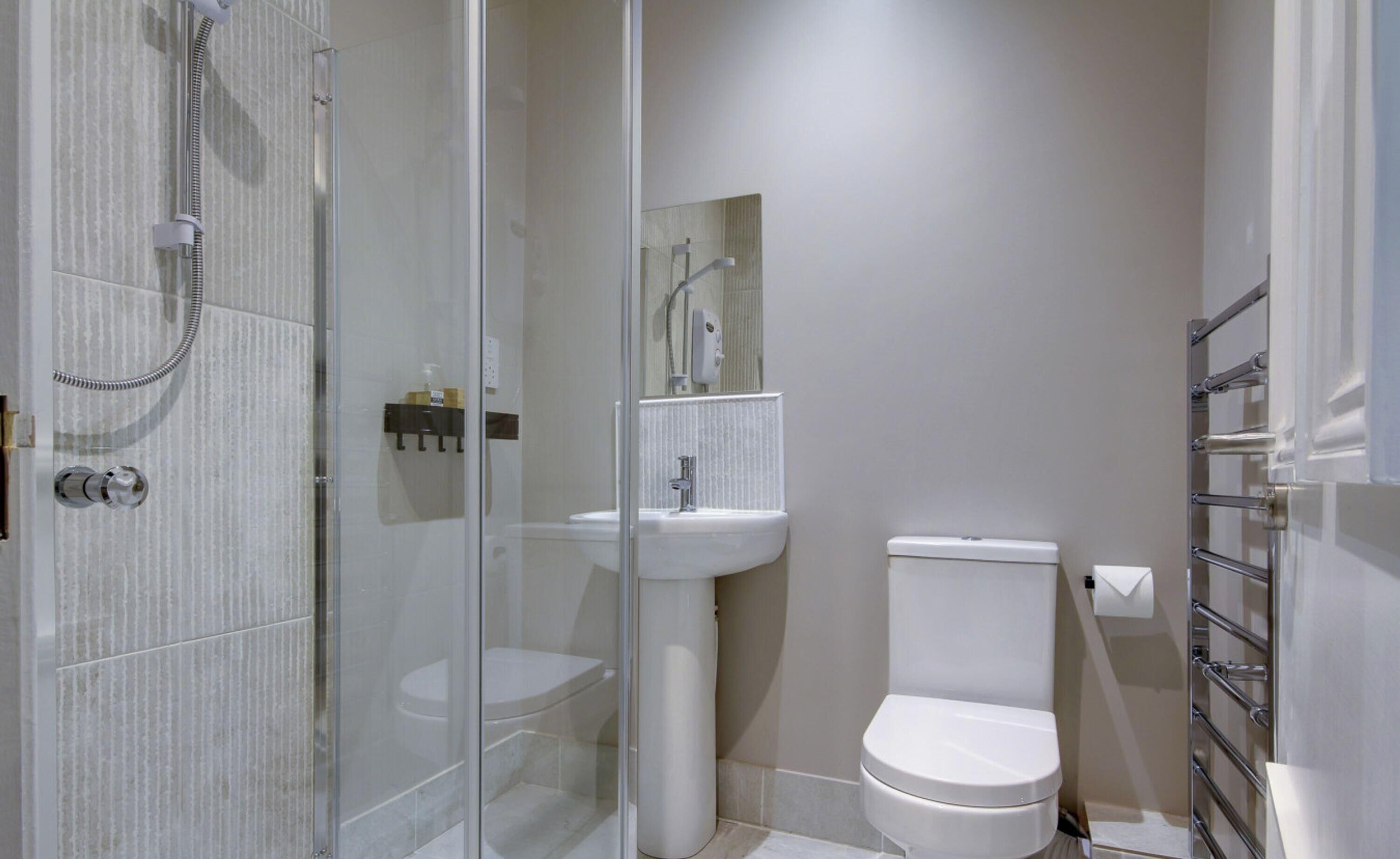 Un bagno moderno con doccia vetro, lavabo su piedistallo e water.