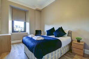A bedroom with a bed, a desk, a chair, a window, and a nightstand. - Contractor Friendly 1-bed Ensuite Ayr Town Centre KA7 (Ayr)