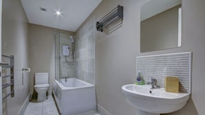 A bathroom with a toilet, shower, bathtub, sink, and a mirror.