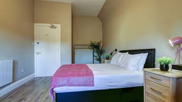 A bedroom with a bed, bedside table, lamp, and a door.