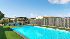 Una piscina rettangolare con una recinzione in legno e un'area verde in primo piano.