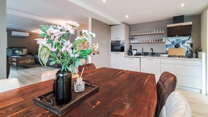 Una cucina moderna con mobili bianchi, un tavolo da pranzo con sedie e un vaso con fiori sul tavolo.