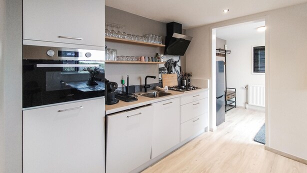 A modern kitchen with white cabinets, a black stove, and a wooden countertop. - Nice home in Stavenisse with sauna (Stavenisse)