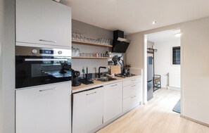 A modern kitchen with white cabinets, a black stove, and a wooden countertop.