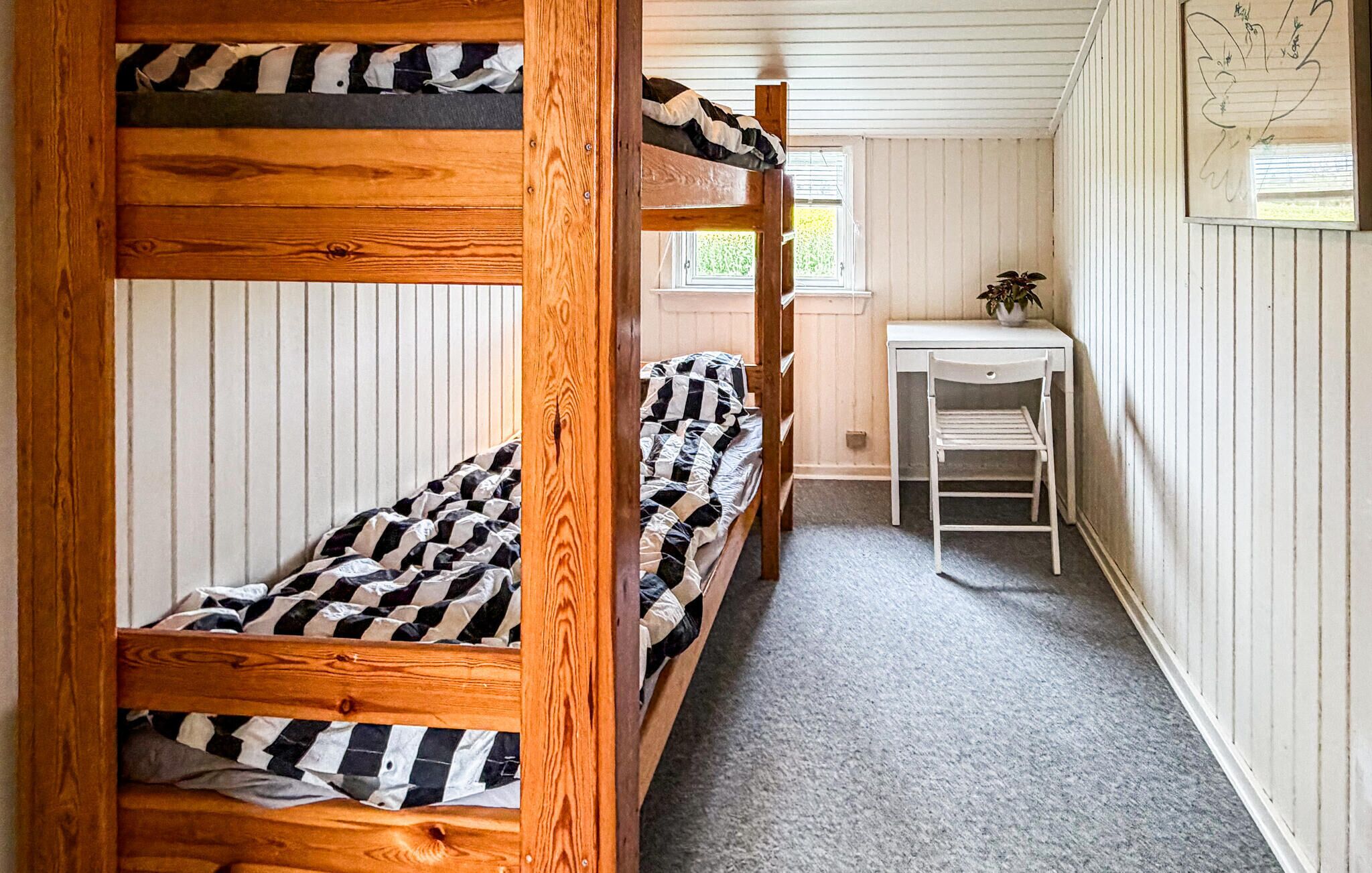 Ein Schlafsaalzimmer mit Etagenbetten, einem Schreibtisch und einem Stuhl.
