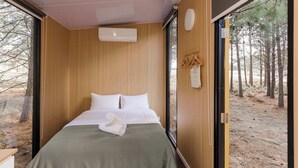 A bedroom with a bed, a window, and a view of trees.