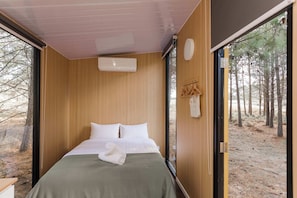A bedroom with a bed, a window, and a view of trees.
