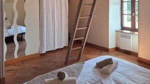 Quarto com um mezanino para dormir, uma escada, uma janela e um radiador.