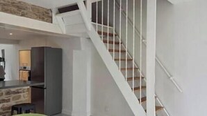 Um interior moderno com escada, área de refeições e cozinha.