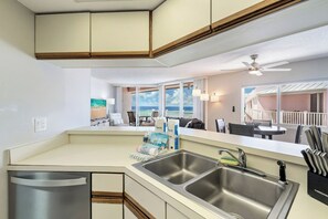 Une cuisine moderne dotée d’un évier à deux bacs, d’un lave-vaisselle et offrant une vue sur l’océan grâce à de grandes fenêtres.