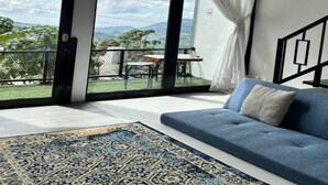 A modern living room with a large sliding glass door leading to an outdoor balcony. - Cabin Athenea Sikapuk (Kejajar)