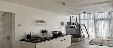 Una cocina moderna con una isla central, armarios blancos y un comedor con vistas al exterior.