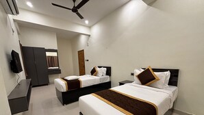 A hotel room with two beds, a TV, a wardrobe, and a ceiling fan. - Thamira Grand Palace (Nagercoil)