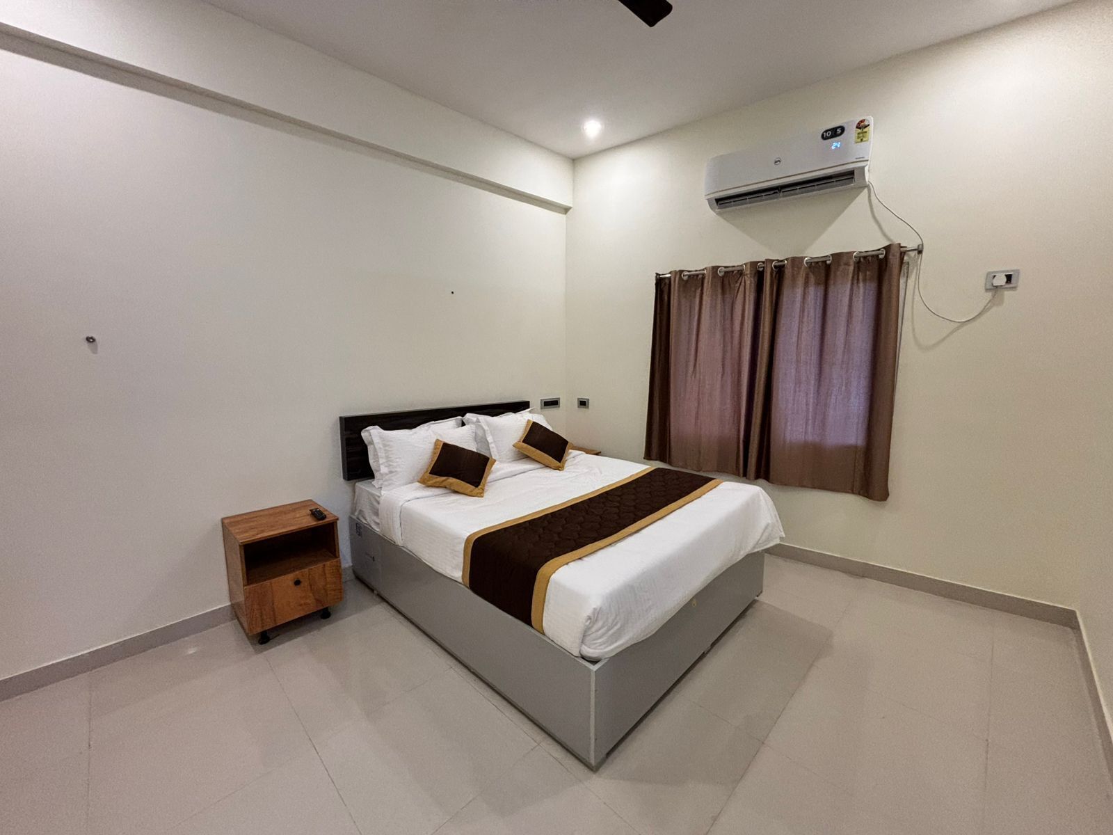 Une chambre à coucher avec un lit, une table de chevet, un climatiseur et une fenêtre avec des rideaux.