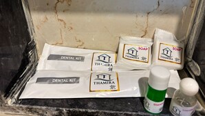 A bathroom with a marble wall, a dental kit, and two bottles of shampoo. - Thamira Grand Palace (Nagercoil)