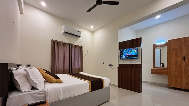 A modern hotel room with a bed, a TV, a ceiling fan, and a wardrobe. - Thamira Grand Palace (Nagercoil)