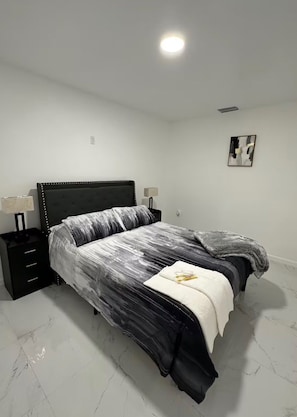 Una camera da letto con un letto, due comodini, un'opera d'arte appesa al muro e una lampada a soffitto.