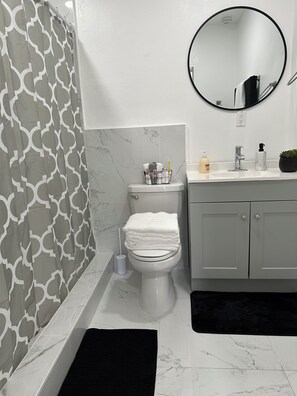 A bathroom with a toilet, a sink, a mirror, and a shower curtain.