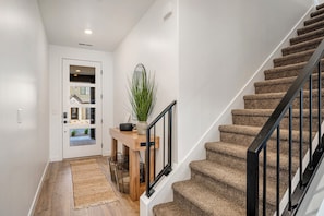 A staircase with carpeted steps and a black railing, leading to a landing with a wooden table and a potted plant. - Brand New Skyline Resort 1737, Private Hot tub, Resort Access, & Near Sand Hollow Lake (Washington)