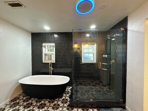 Un baño con una bañera independiente, ducha con mampara de vidrio y baldosas de diseño.