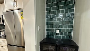 A kitchen with stainless steel appliances, a tiled backsplash, and a black refrigerator. - Cute Tampa House Near USF & Downtown (Tampa)