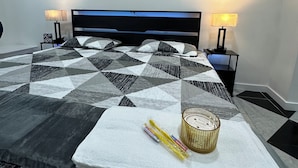 A neatly made bed with a geometric patterned bedspread, two bedside lamps, and wall art. - Cute Tampa House Near USF & Downtown (Tampa)
