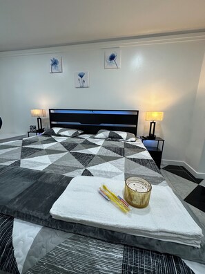 A neatly made bed with a geometric patterned bedspread, two bedside lamps, and wall art.