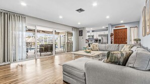 Ein modernes Wohnzimmer mit grauem Sofa, einem Couchtisch und Blick auf einen Pool sowie eine Sitzgelegenheit im Freien.
