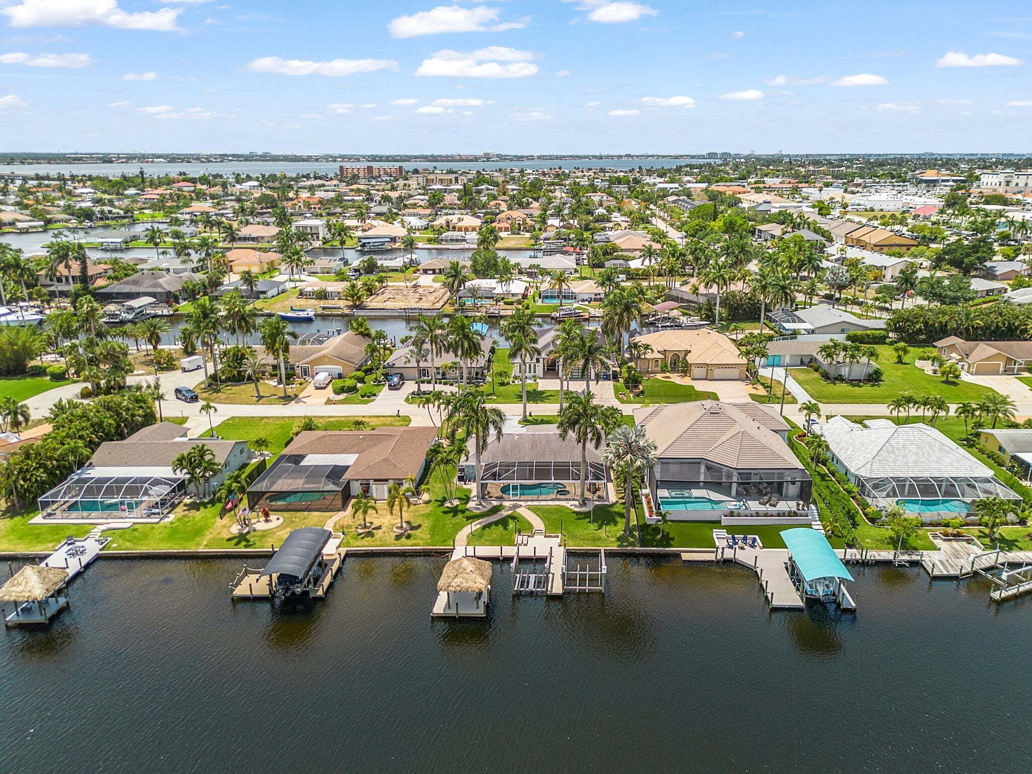 A residential area with houses, palm trees, and docks with boats.