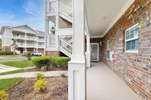 A multi-story building with a brick facade, white railings, and a covered entrance. - Golf course view condo with screened-in patio, W/D, pool & close to beach (North Myrtle Beach)