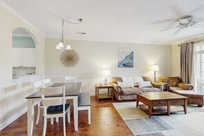 A modern living room with a dining table, sofas, and a ceiling fan. - Golf course view condo with screened-in patio, W/D, pool & close to beach (North Myrtle Beach)