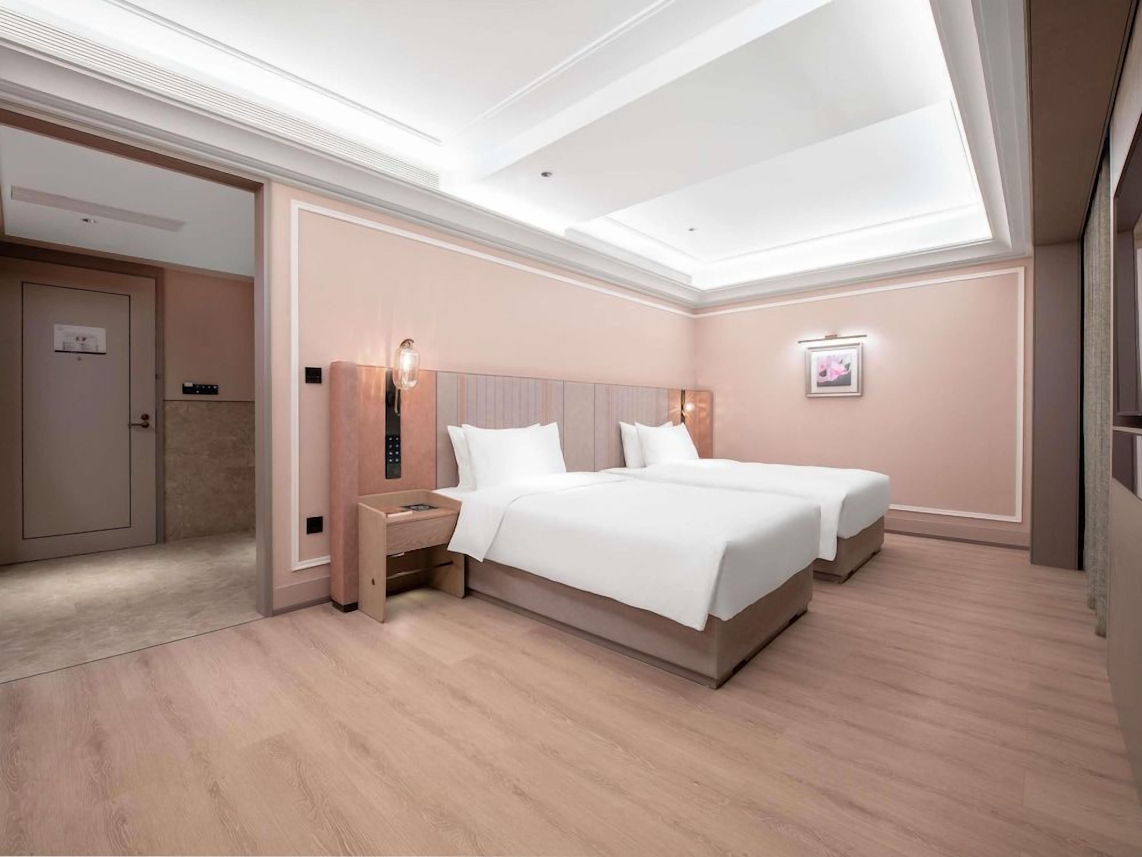 Habitación de hotel con una cama grande, mesitas de noche, una lámpara de pared y una puerta.