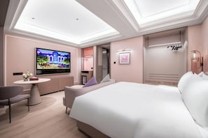 Una habitación de hotel moderna con cama, televisión, zona de estar y baño.