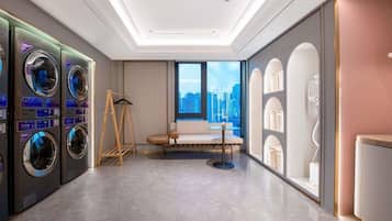 A hotel room with a city view, a sofa, a small table, and a washing machine.