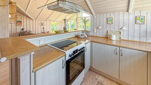 A kitchen with a stove, oven, and wooden cabinets. - Cozy home in Dannemare with WiFi (Dannemare)