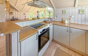 Eine Küche mit Herd, Backofen und Holzschränken.