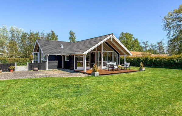 A modern house with a large deck, a garage, and a well-maintained lawn. - Cozy home in Dannemare with WiFi (Dannemare)