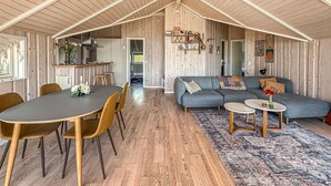 A spacious living area with a dining table, sofa, and a kitchen in the background. - Cozy home in Dannemare with WiFi (Dannemare)