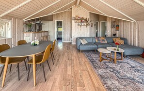 Ein geräumiger Wohnbereich mit Esstisch, Sofa und einer Küche im Hintergrund.