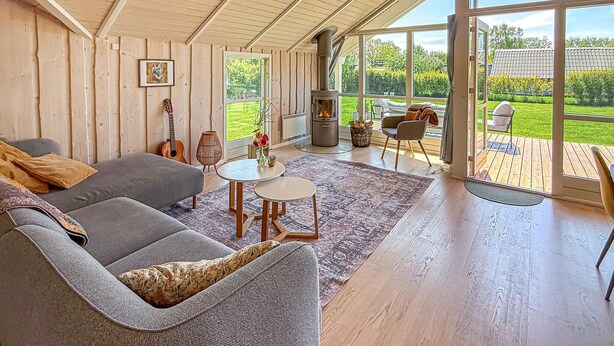 A spacious living room with a large sofa, a small table, and a fireplace. - Cozy home in Dannemare with WiFi (Dannemare)
