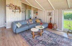 Ein gemütliches Wohnzimmer mit einem grauen Ecksofa, einem kleinen runden Couchtisch und einem gemusterten Teppich.