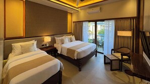 Ein Hotelzimmer mit zwei Betten, einem Deckenventilator, einem kleinen Tisch und Blick ins Freie.