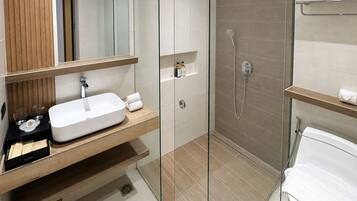 A modern bathroom with a glass-enclosed shower, a wooden vanity, and a white toilet.