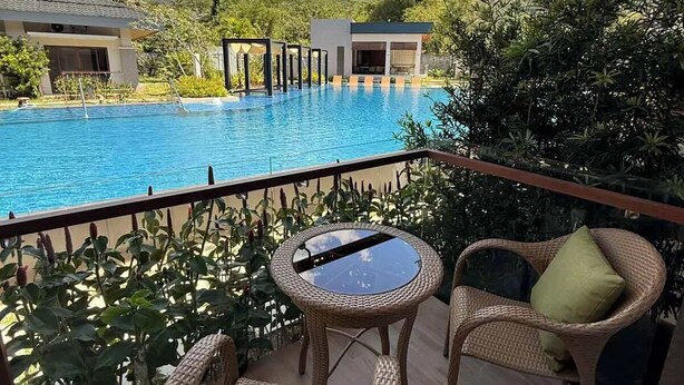 Ein Balkon mit Pool, Korbmöbeln und Blick auf die umliegende Landschaft.