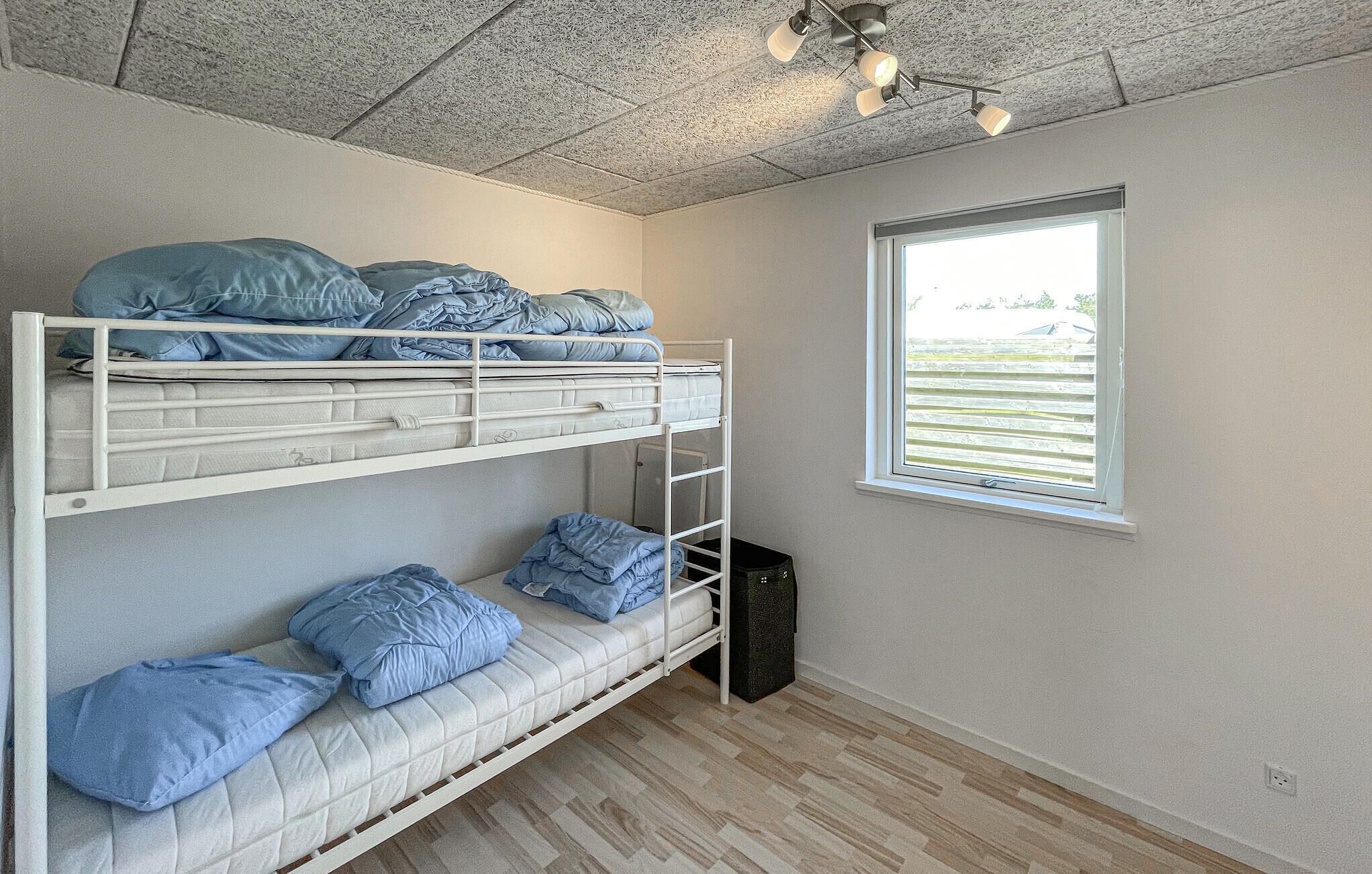 Dormitorio con literas, ventana y ventilador de techo.